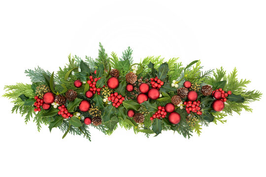 Christmas decoration with red bauble decorations, winter holly with berries, mistletoe, ivy & cedar cypress fir leaves on white background. Decorative display for the festive season. Copy space.