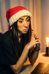 Chica con gorro de papa noel realizando vlog en su cuarto y trabajando en el pc