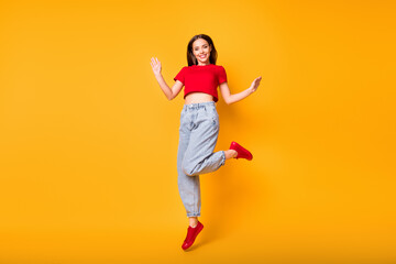 Fototapeta na wymiar Full length photo of cute jumping lady wear red crop top jeans shoes isolated yellow color background