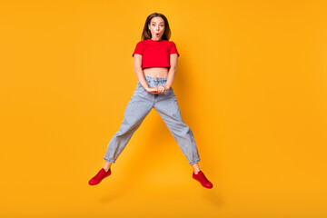 Fototapeta na wymiar Photo of shocked jumping lady open mouth wear red crop top jeans shoes isolated yellow color background