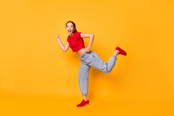 Full size profile photo of lady stand on one leg making step wear red crop top jeans shoes isolated on yellow color background