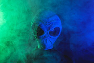 Alien is hiding in the smoke on dark background.