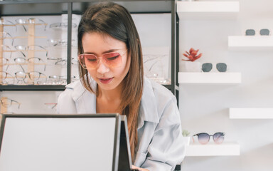 Asian young woman shopping eyeglasses in glasses store. Optical and Sales Promotion Concept.