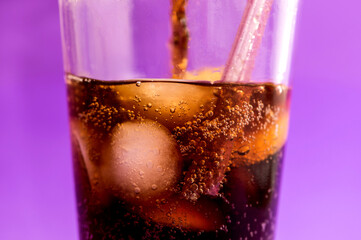 detail of fizzy and carbonated cola drink on purple background