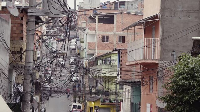 Establishing shot of one of the largest slums of Latin America. In the scene brick houses in a narrow street covered with power cables in a poor suburban neighbourhood.