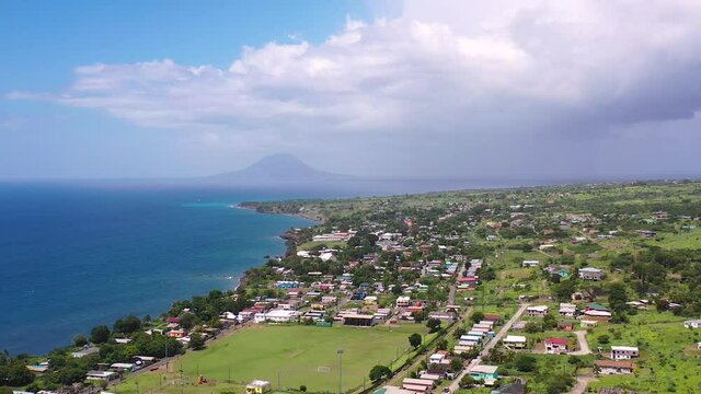 Coastal town in St. Kitts,Lesser Antilles,Caribbean below a green mountainside.
