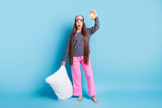 Full length photo of cute pretty teenager girl shocked open mouth hold clock pillow overslept university wear mask dotted shirt pink pants pajamas sleepwear isolated blue color background