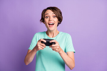 Photo of childish cute young lady wear casual teal outfit holding playing gamepad isolated purple color background