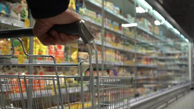 senior hands pushing trolley in supermarket, department store or shopping mall. lifestyle concept. outside the home. blur background with copy space