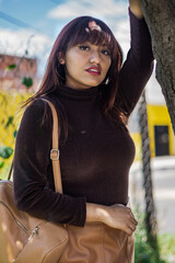 young brunette girl leaning on a tree in the city park