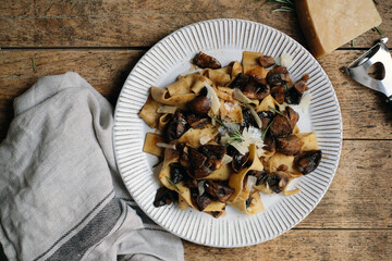 Rustic delicious pasta with roasted mushrooms, parmesan cheese and rosemary on the wooden table