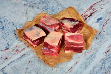 Raw beef ribs on brown food paper on a light natural stone background. Raw Organic Beef Short Ribs