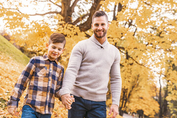 Fototapeta premium Happy family father and child boy in the autumn leaf fall in park holding hand together