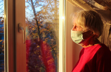 The Covid-19, health, safety and pandemic concept - senior old lonely woman sitting near the window