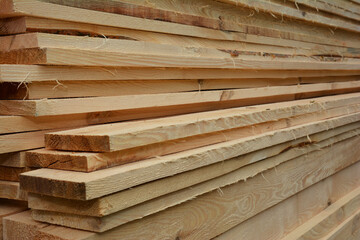 A close-up of a stack of pine boards, appearance lumber, wood panel boards and planks neatly piled up together.