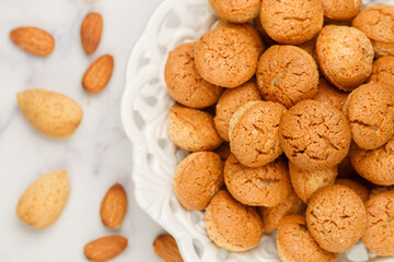 Amaretti-traditional Italian almond cookies in a white plate on a marble top view background. Amarettini biscuits close-up. Selective focus