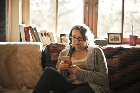 woman at home on a sofa writes on a smartphone