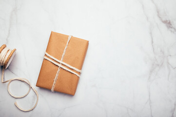 Gift wrapped in recycled brown paper, on light background with minimalist style wrapping, top view flat lay