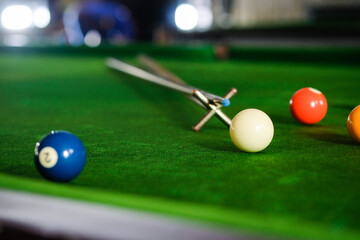 Man's hand and Cue arm playing snooker game or preparing aiming to shoot pool balls on a green...