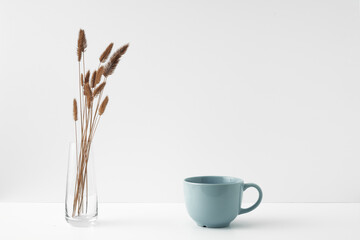 Mug and transparent vase with flowers on a white background. Eco-friendly materials in the decor of...