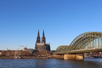 Naklejka premium The Hohenzollern bridge over Rhine river on a sunny day. The Cologne Cathedral (Kolner Dom) in the city of Cologne, Germany. It is the largest Gothic church in northern Europe.