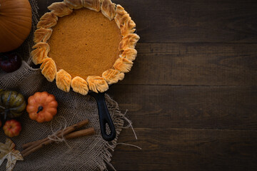Homemade pumpkin pie baked in cast iron pan, on wooden background