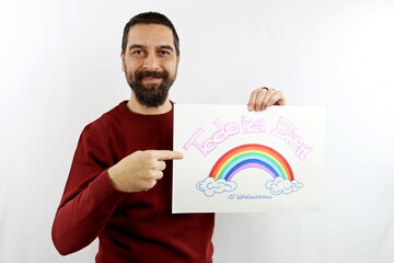 Young bearded man, smiling, holds a sign in his hand with the inscription in Spanish 