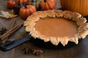 Homemade pumpkin pie baked in cast iron pan, on wooden background
