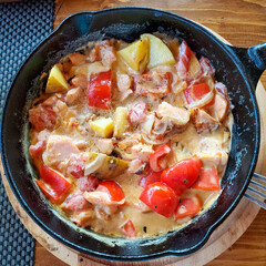 top view, vegetables with salmon in a cast-iron pan served on a wooden Board.