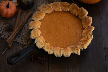 Homemade pumpkin pie baked in cast iron pan, on wooden background