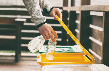 The woman is throwing the glass into one of three trash bins