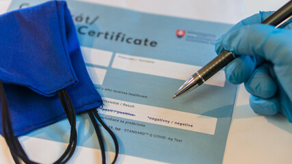 laboratory assistant analyses negative PCR certificate of covid-19 in on white table with pen and...