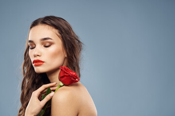 woman with a rose in her hands naked shoulders evening makeup red lips