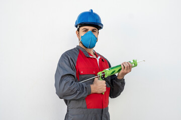 Worker man with silicone gun and protective mask ready to work repairing joints