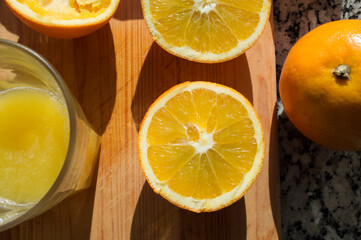 Fototapeta na wymiar primer plano, visto desde arriba de una naranja y mitad junto a un zumo de naranja, sobre tabla de madera. 
