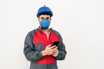 Bearded worker man with face mask looking smart phone