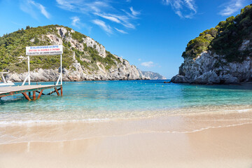 Empty beach of Agios Spyridon bay in Corfu island in Greece, surrounded by rocks on a sunny holiday...