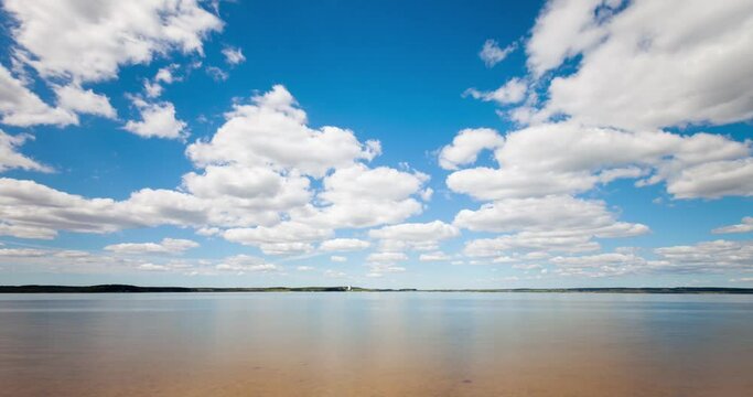 Time lapse of clouds forming over a lake. View through stones in the water.