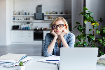upset blonde woman in eyeglasses working from home
