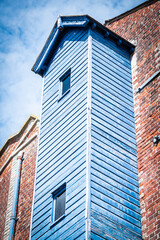 A Blue Wooden Extension With A Brick Wall Building And Blue sky