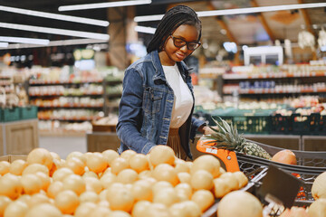 African woman with shopping cart. Girl in a supermarket.
