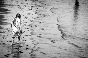 A Young Girl Plays In The Low Waves On The Beach
