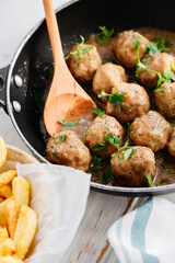 Meatballs in sauce in a pan with fries