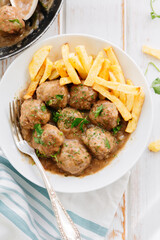 Meatballs in sauce with parsley and fries