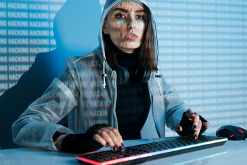 Internet, crime, cyber attack, system breaking concept. Blue neon light background. Woman hacker is working on a code with digital interface all around.