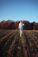 Naklejka na ściany i meble Beautiful fashionable young woman dressed in white sportswear outdoor autumn