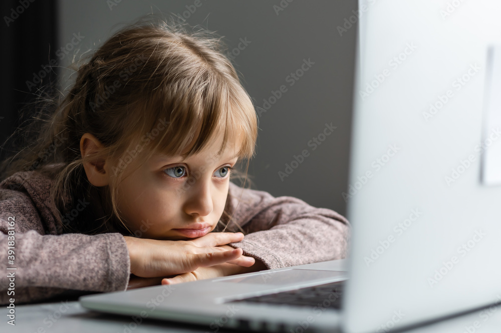 Wall mural bored little girl with laptop at home. cute child doing homework on computer. modern online educatio