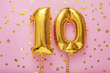 10 air balloon numbers on pink background. 10 k gold foil balloons with confetti. Birthday party...