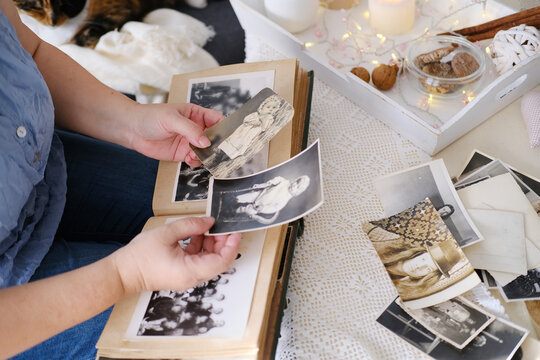 woman looking through her old photographs 1965-1970, the concept of nostalgia and memories of youth, childhood, remembering her life, relatives, family connection of generations