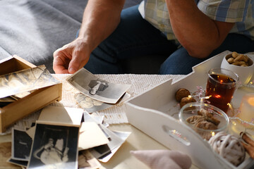 an elderly man looks through his old photographs of 1960-1965, the concept of nostalgia and memories of youth, childhood, remembering his life, relatives, family connection of generations